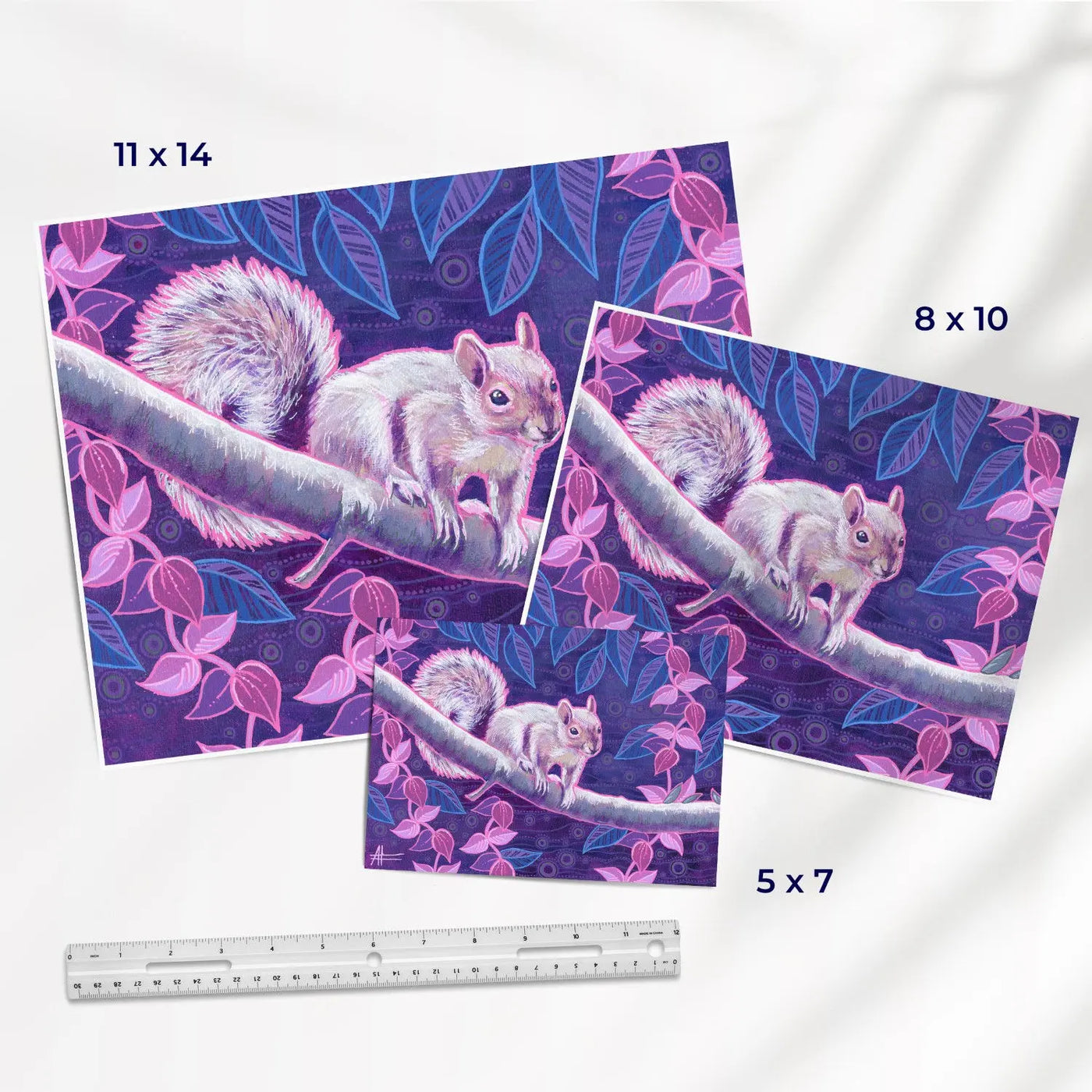 Set of three squirrel art prints, showcasing varying sizes with a purple and pink leafy motif.