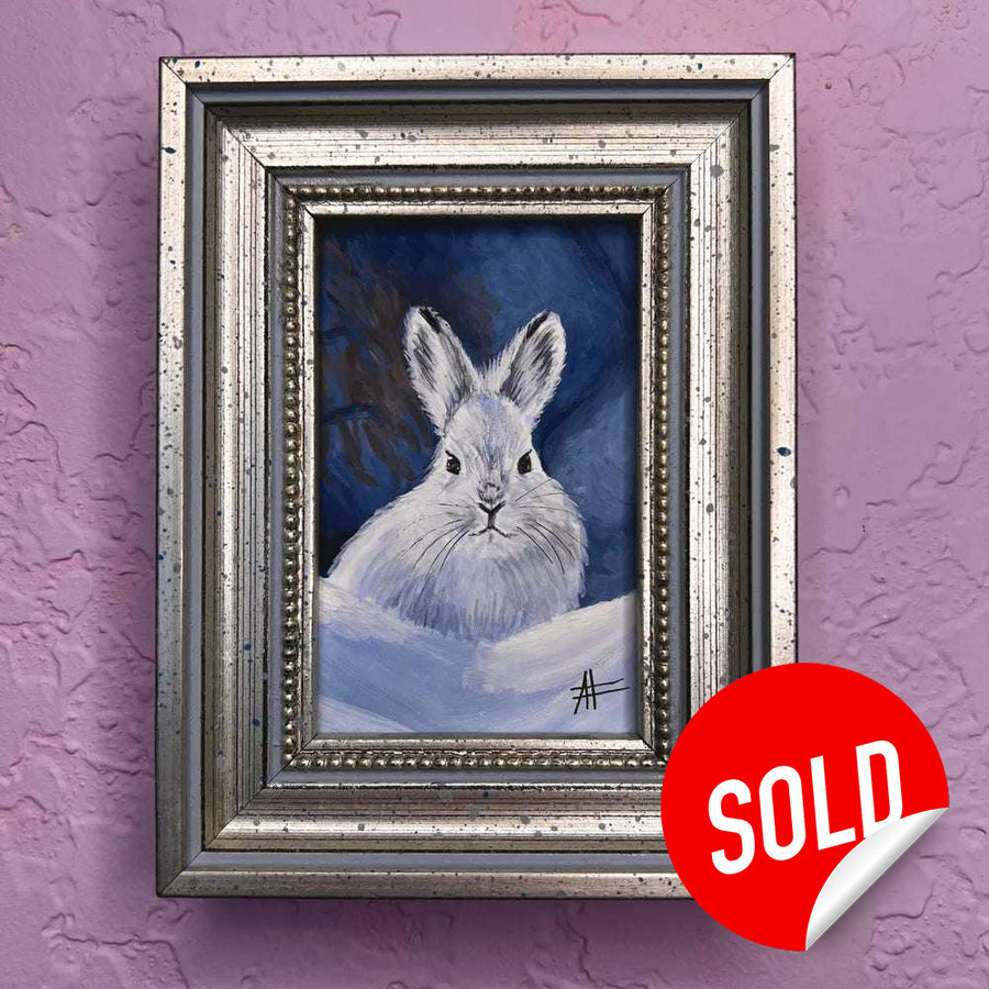 Snow rabbit mini portrait in vintage silver frame on purple wall with a red sold sticker in the bottom right corner